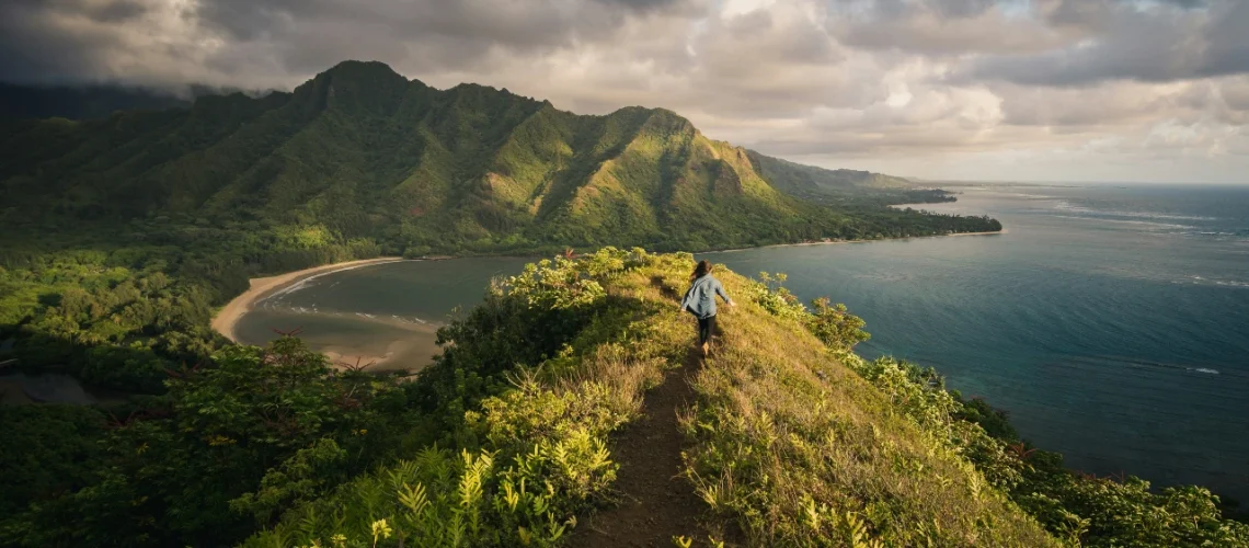 Traveler hiking on a scenic trail surrounded by mountains and greenery as an option for many sober activities.